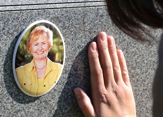 Woman placing her hand on a headstone with ceramic headstone picture